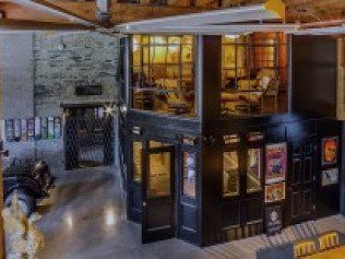 Interior with a two-story structure, black doors, posters, and a seating area visible upstairs.