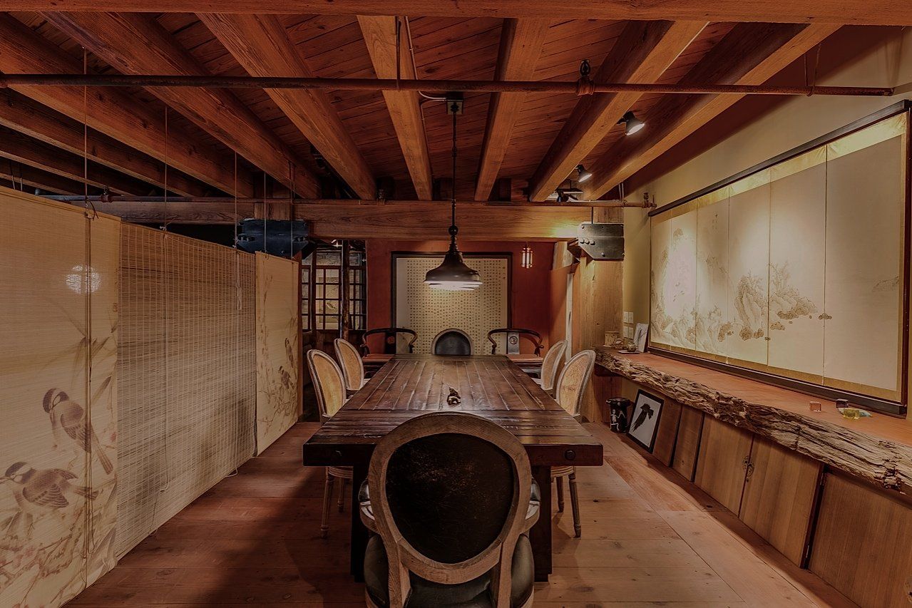 Long wooden dining table in a room with wood paneling, artwork, and a hanging light fixture.