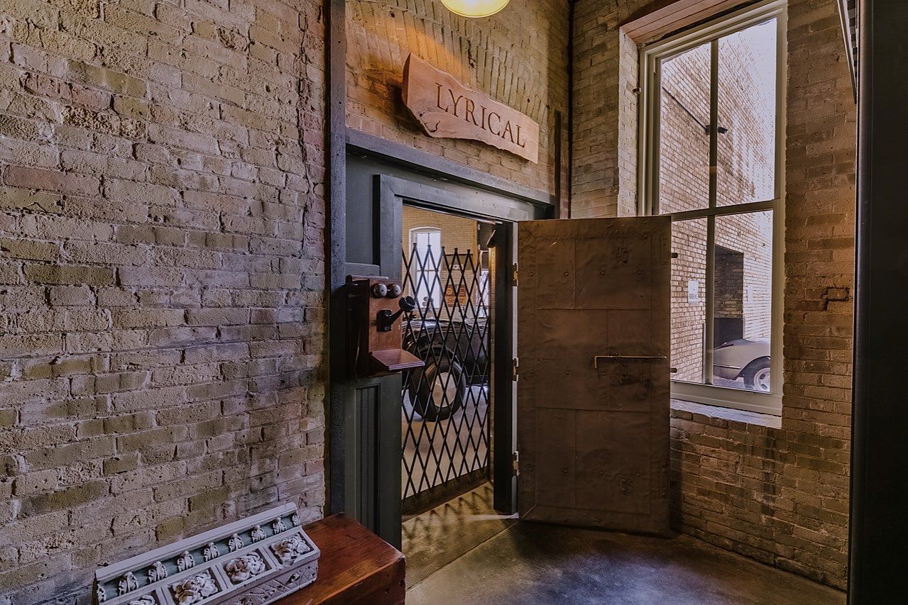 An entryway with a brick wall, open door, and antique decor.