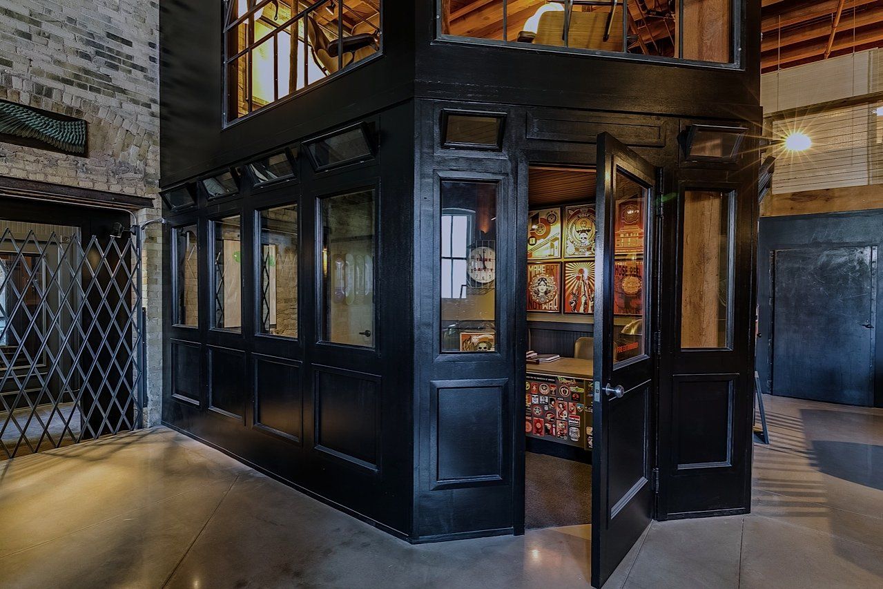 Black booth with open doors, multiple windows, interior display of packaged items, and an elevator next to it.