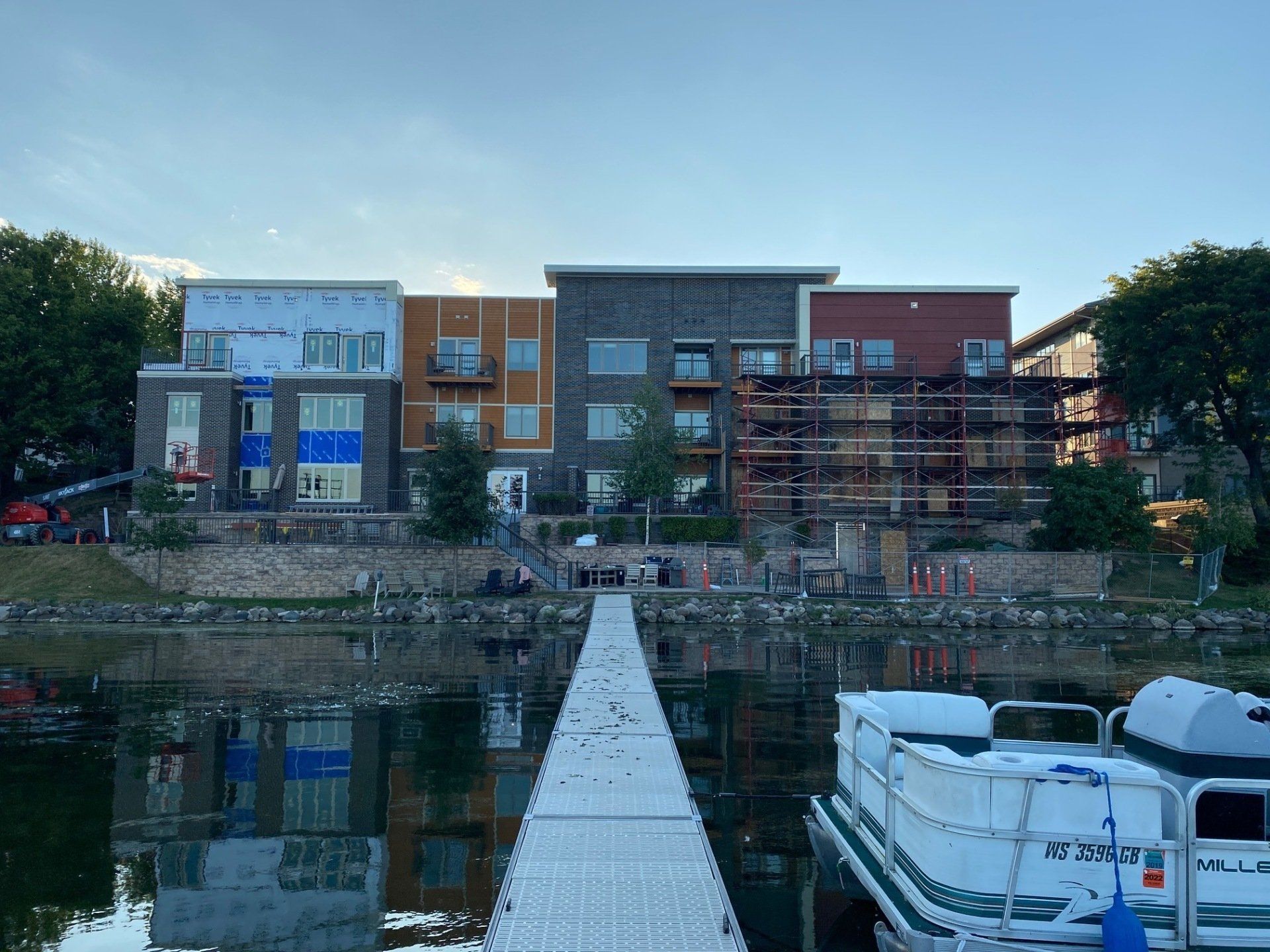 Row of colorful buildings on a lake shore with a white dock in front and a boat in the foreground.