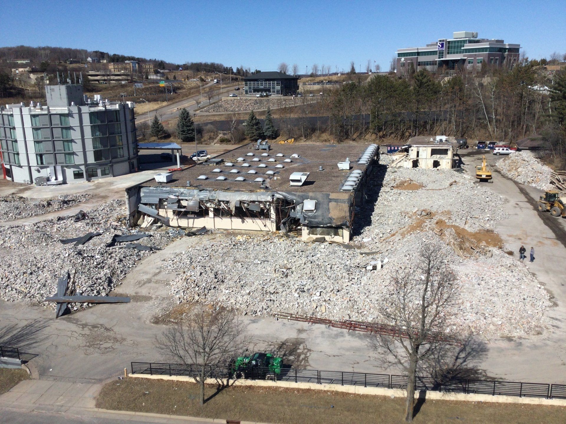 Demolition of a building site with rubble, buildings, and construction equipment.