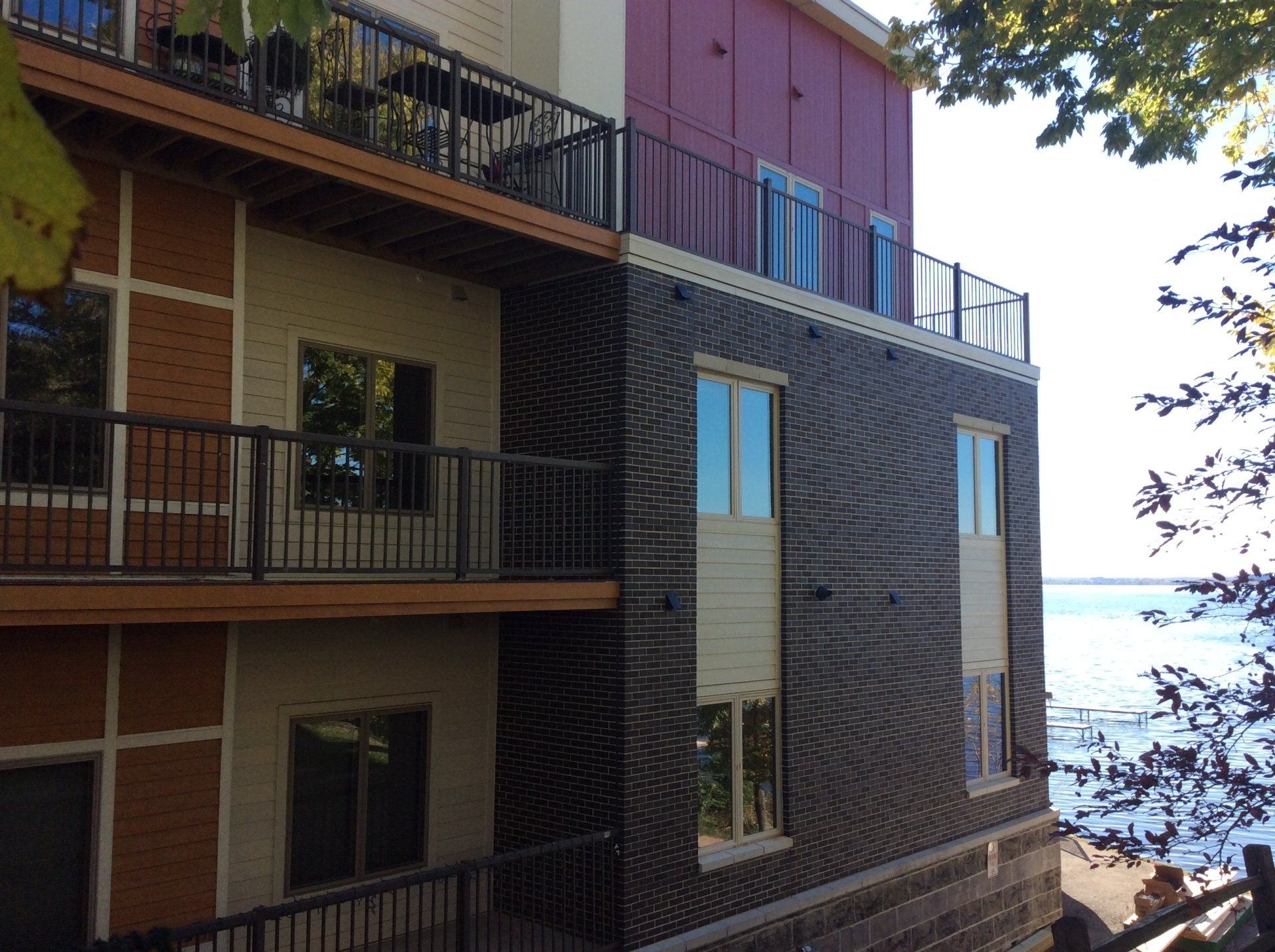 Multi-story brick and red building with balconies, near water.