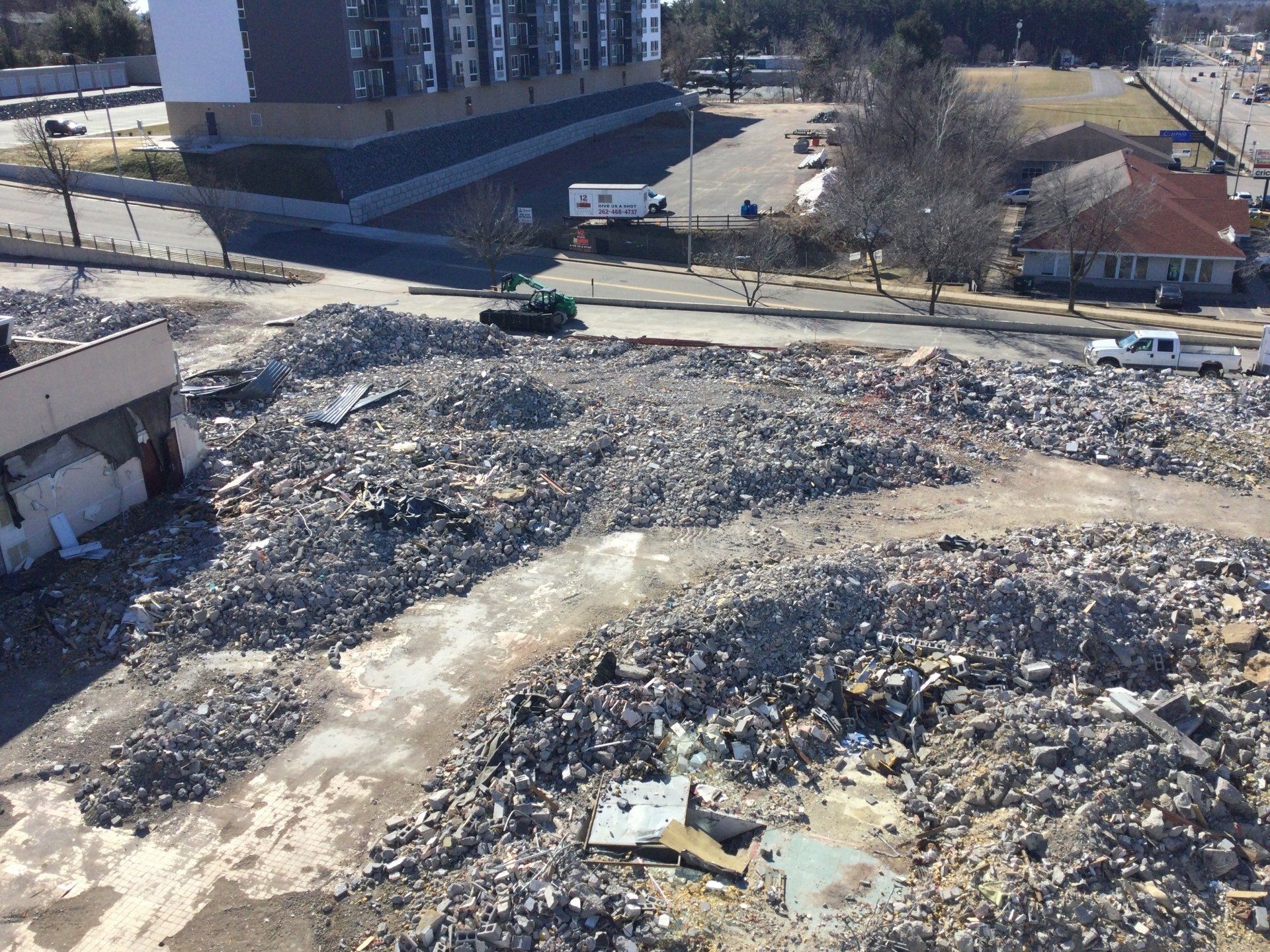 Debris from a demolished building, with a road and other buildings in the background.