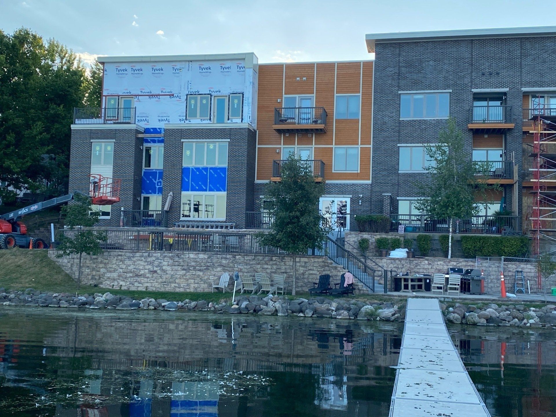 Row of waterfront townhomes under construction, blue, brown, and gray siding, small balconies.