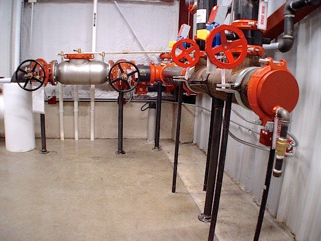 Fire sprinkler system pipes and valves in an industrial setting, with red and black accents.
