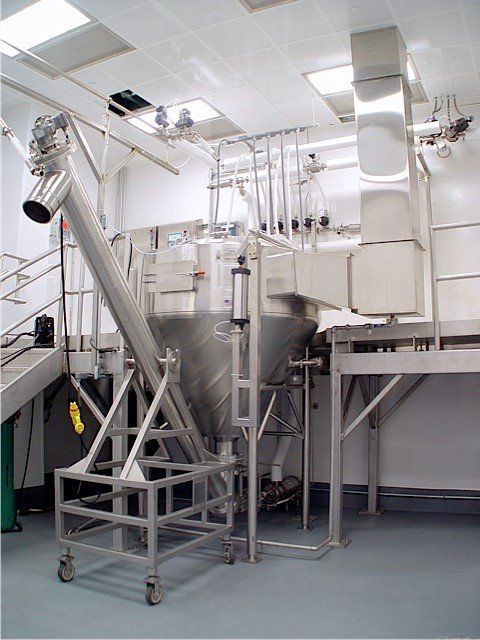 Stainless steel industrial mixing and conveying equipment in a clean room setting.
