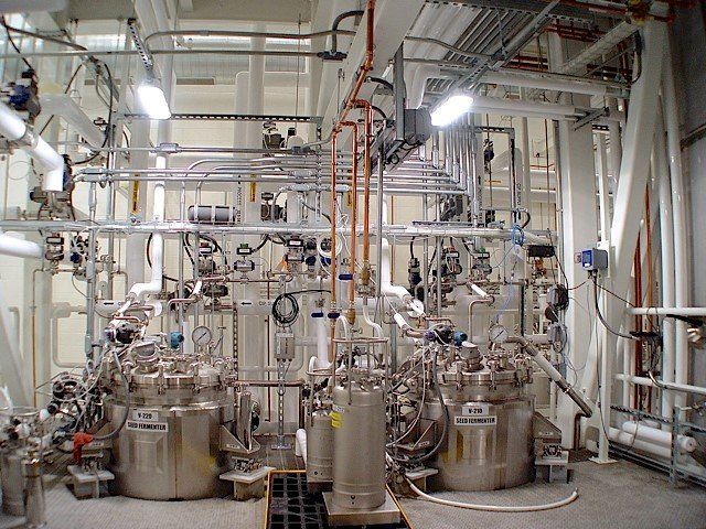 Industrial facility with stainless steel tanks, pipes, and control equipment.
