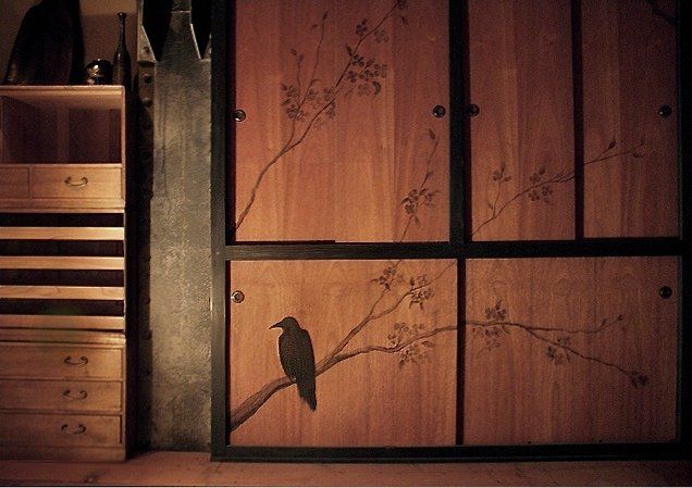 Wooden cabinet with a painted raven on a branch; cherry blossom design.
