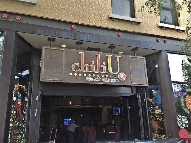 Chili U restaurant entrance with sign above doorway. Brown and black exterior, people inside.