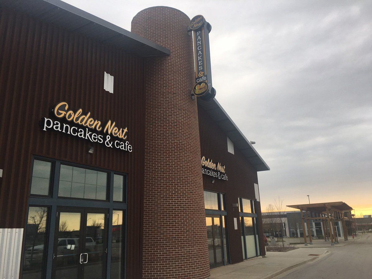 Golden Nest Pancakes & Cafe restaurant exterior with a brick column and signage.