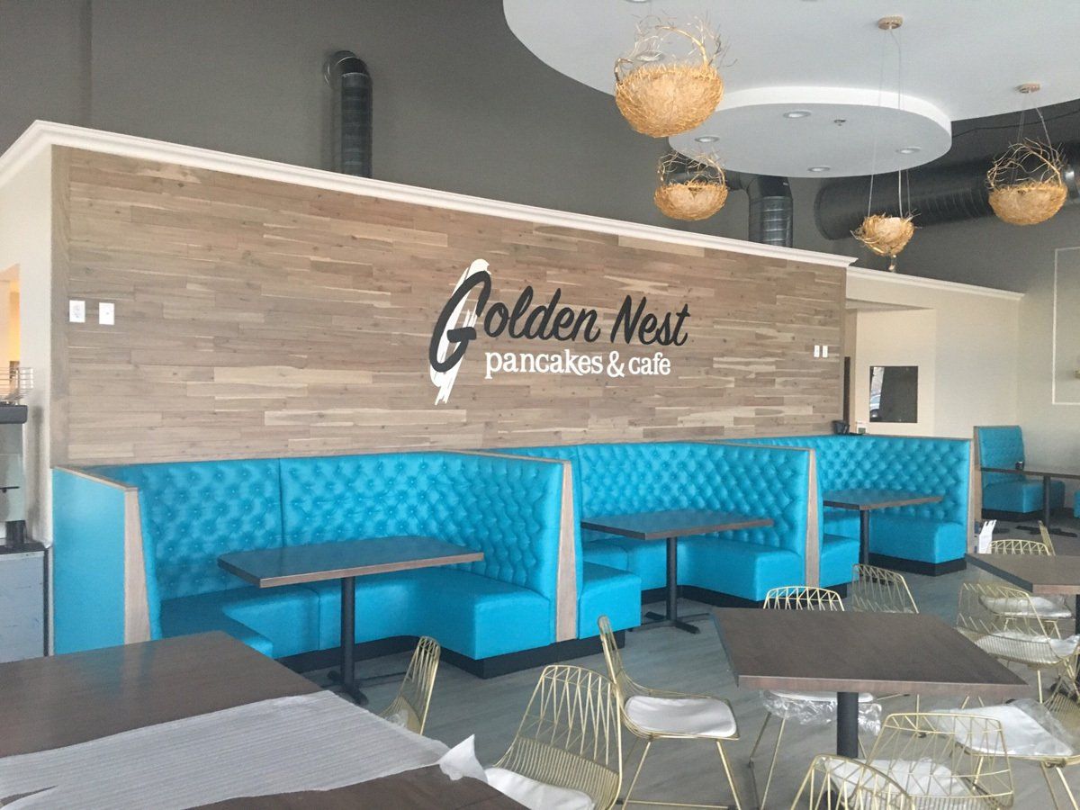 Inside Golden Nest Pancakes & Cafe with turquoise booths, wooden wall, and tables.
