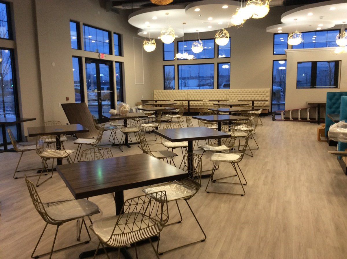 Empty dining area with tables, chairs, and large windows. Soft lighting and neutral color scheme.