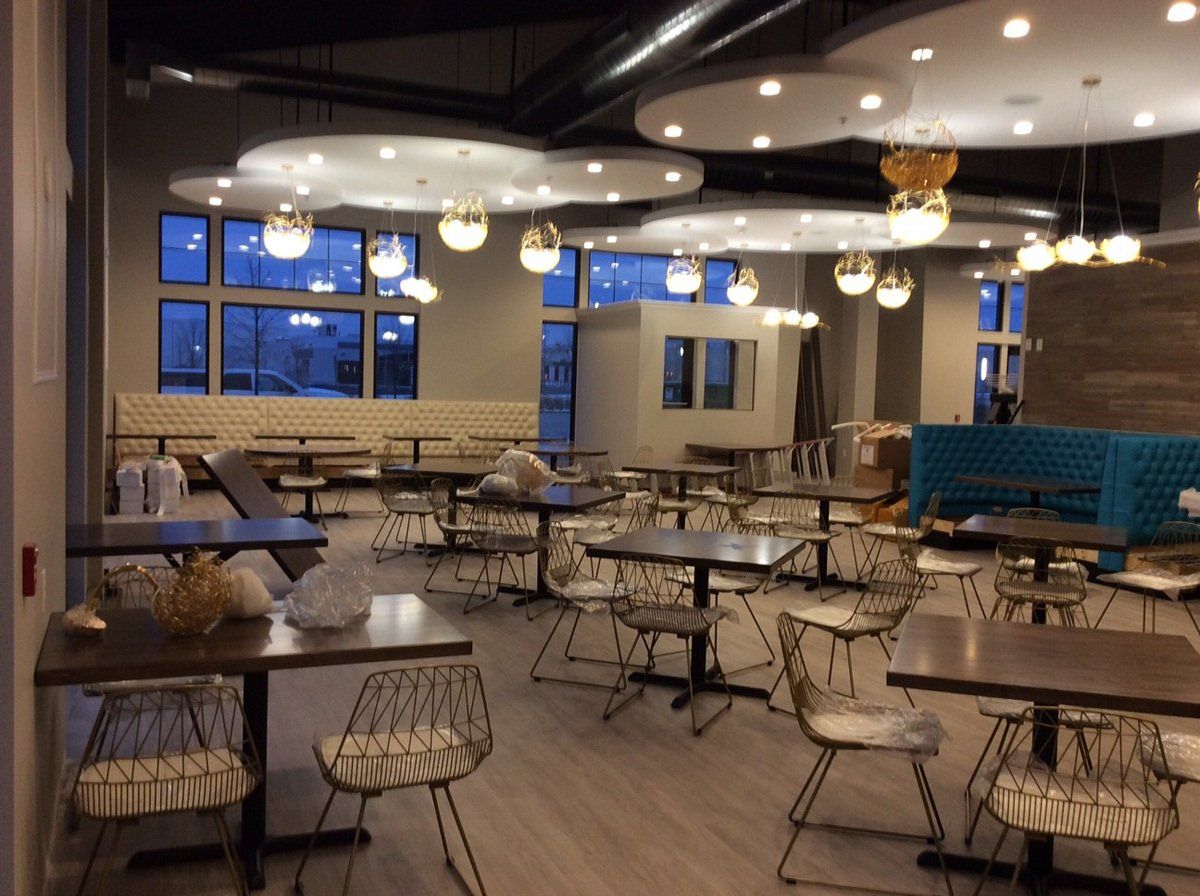 Restaurant interior with tables and chairs, decorative cloud-shaped ceiling lights, and large windows.