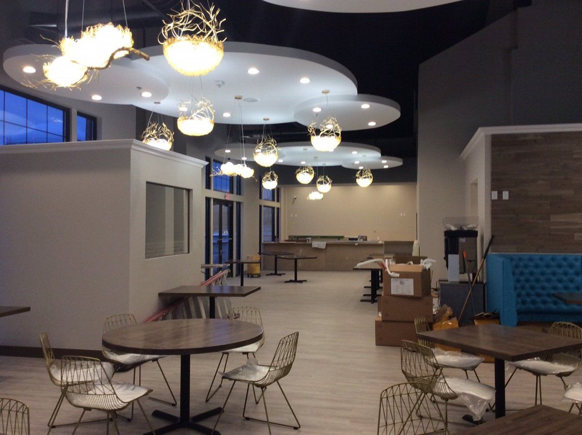 Empty restaurant interior with cloud-shaped ceiling lights, tables, and seating.