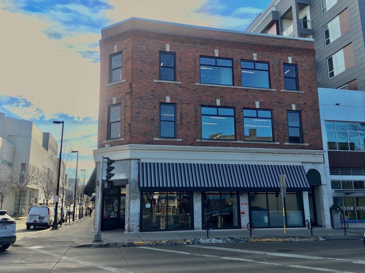 Brick building with awning, large windows, and street view.