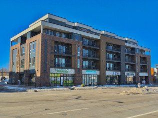 Multi-story building with commercial storefronts and residential units; brick and blue facade.