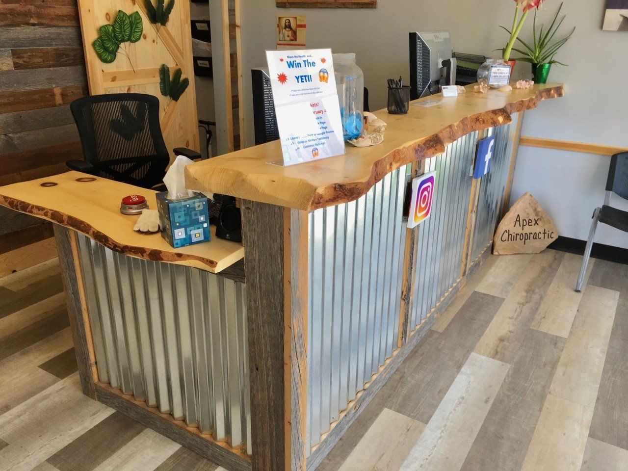 Reception desk with corrugated metal and live edge wood trim. Social media icons visible.
