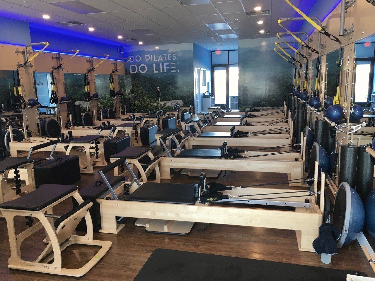 Pilates studio interior with reformer machines, blue accents, and a mural that says 