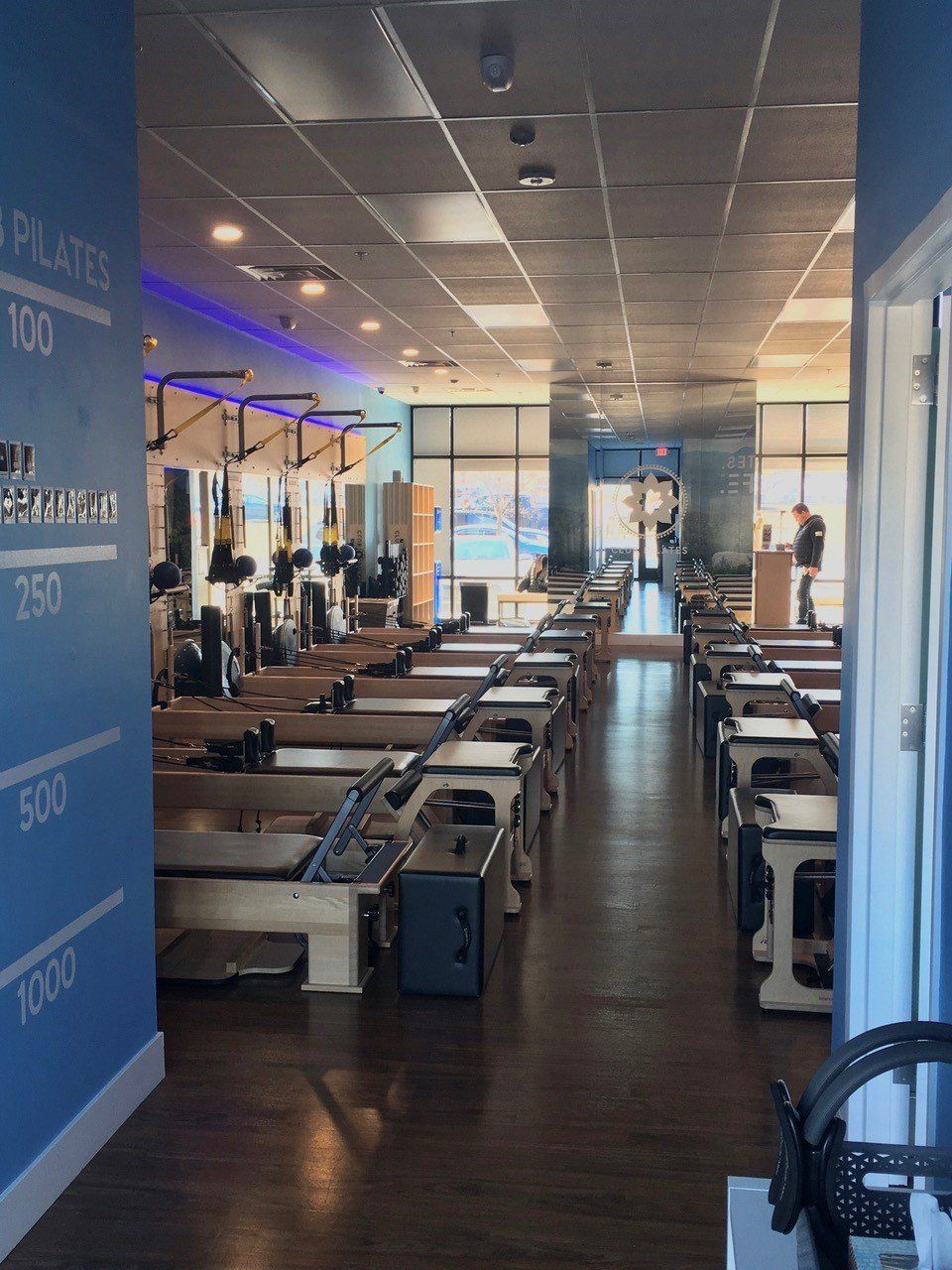 Pilates studio with rows of reformers; blue wall with numbered milestones.