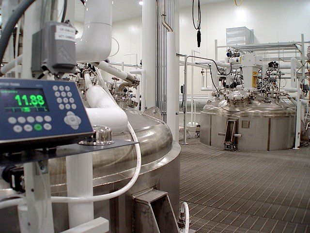 A laboratory with industrial-sized tanks and a digital display showing a weight of 11.88.