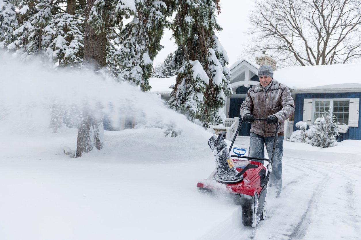 person using snow blower in driveway of home