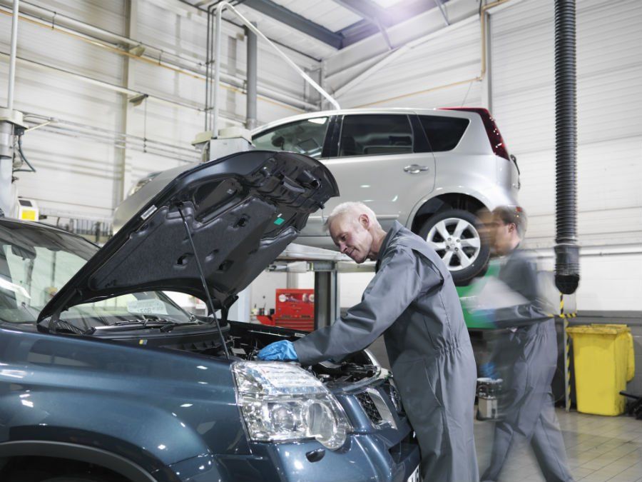 mechanics working under hood of a car