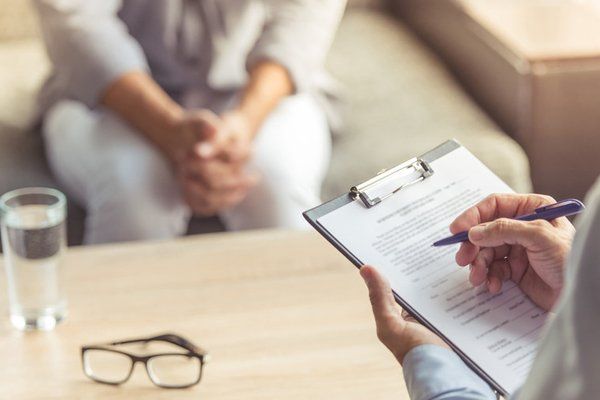 Cropped image of depressed man at the psychotherapist. Doctor is making notes while listening to his patient