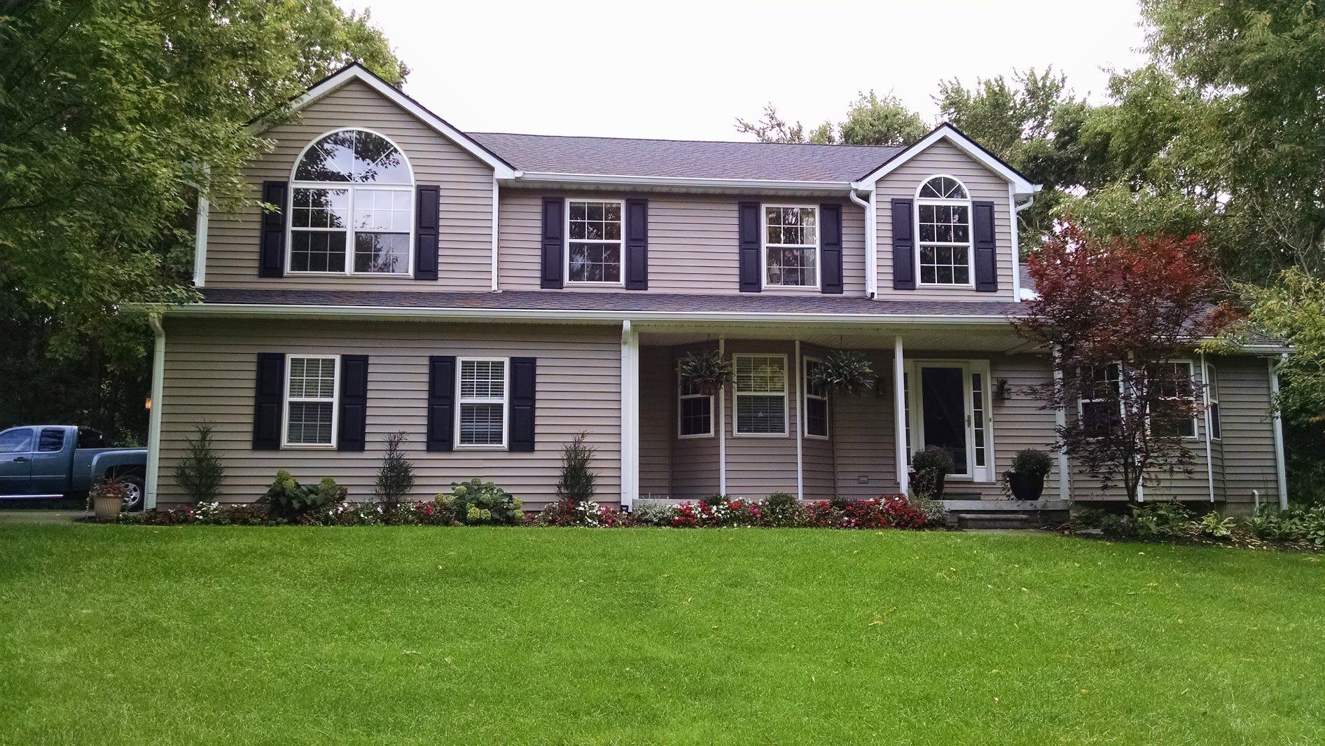 Two-story gray house with black shutters, white trim, and a green lawn in front