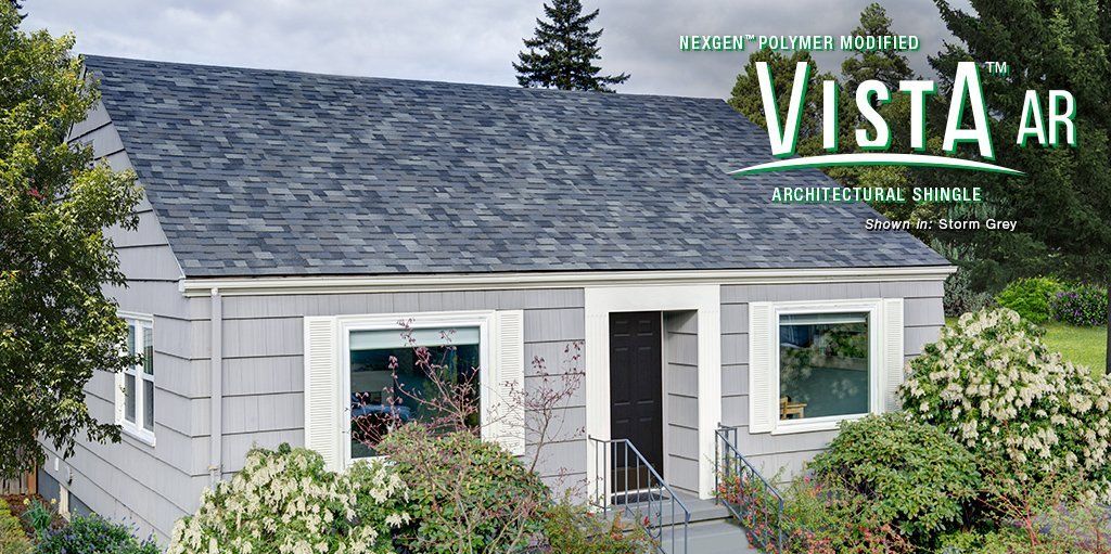 White cottage with gray shingle roof and bushes in front, with Vista AR logo overlaid at top right