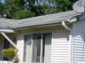 White house exterior with sliding glass door, gutter, satellite dish, and flowers by the porch