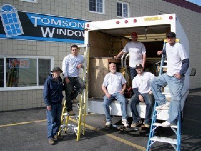 The Tomson Window team sitting in and standing next to a moving van, outside their storefront location Grand Island, NY