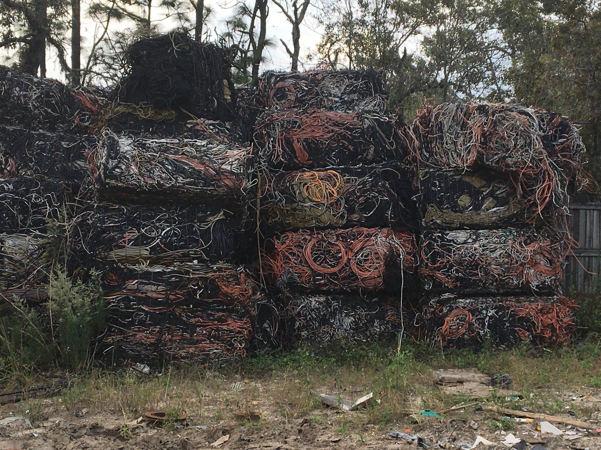 A large pile of scrap metal is stacked on top of each other in a field.