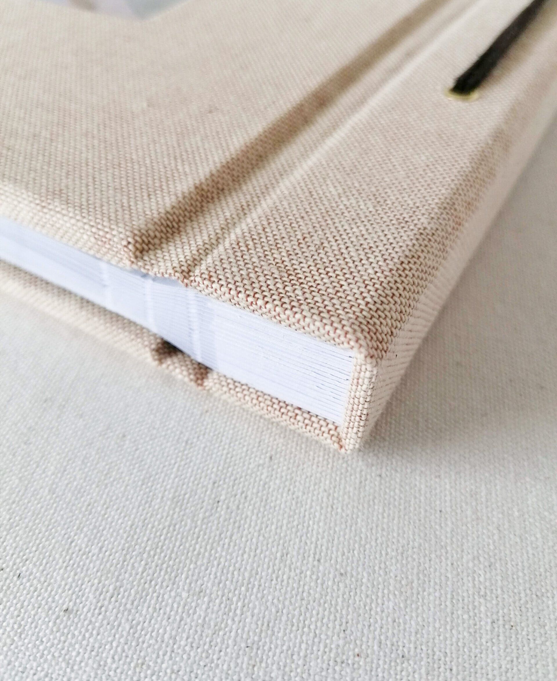 An image of a Peach linen landscape memory book photo album. The image shows details of the album spine and neatly bound white page edges. The album is laid on a white background.