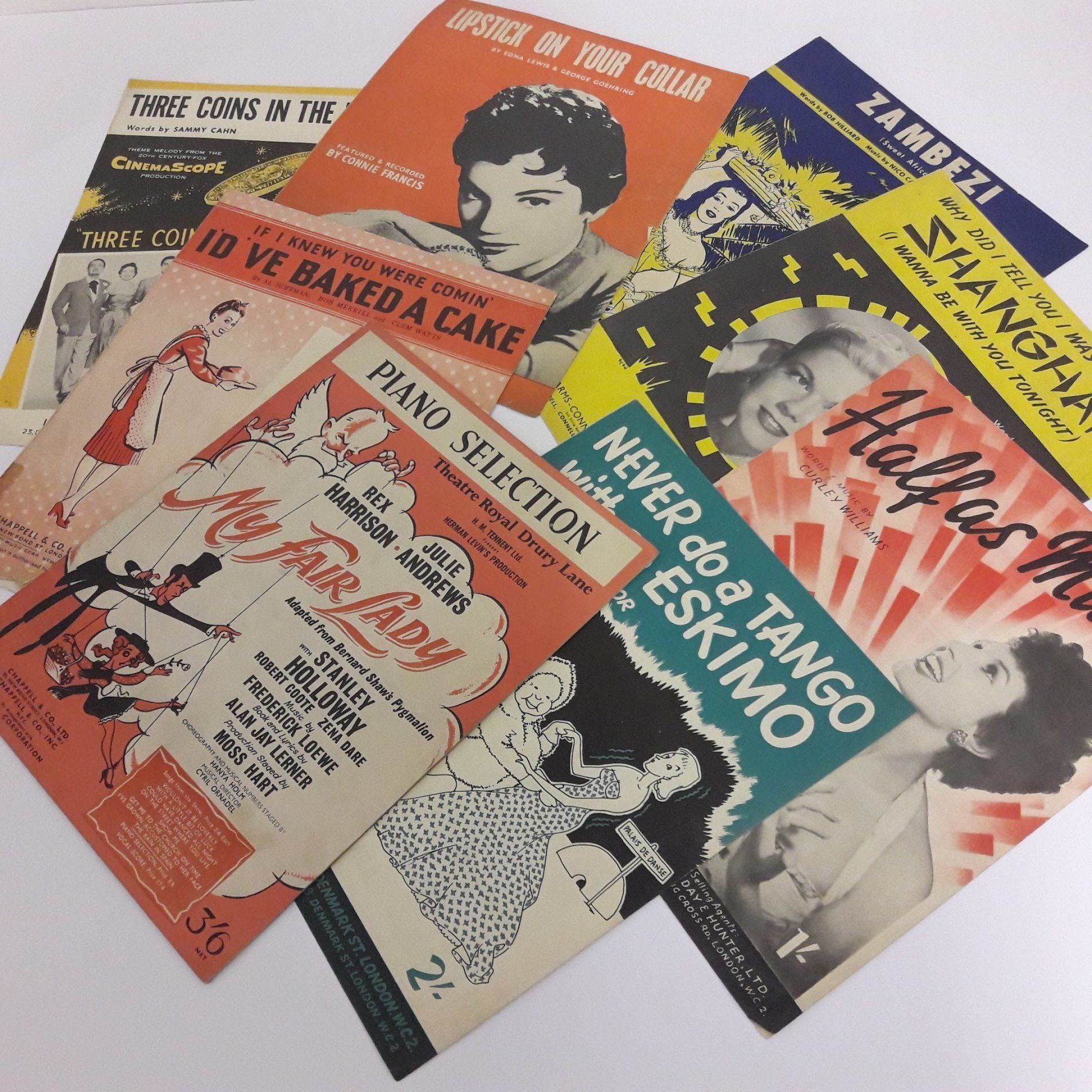 The image shows various colourful Vintage mid century sheet music covers. There are illustrations for my fair lady and never do a tango with an eskimo.