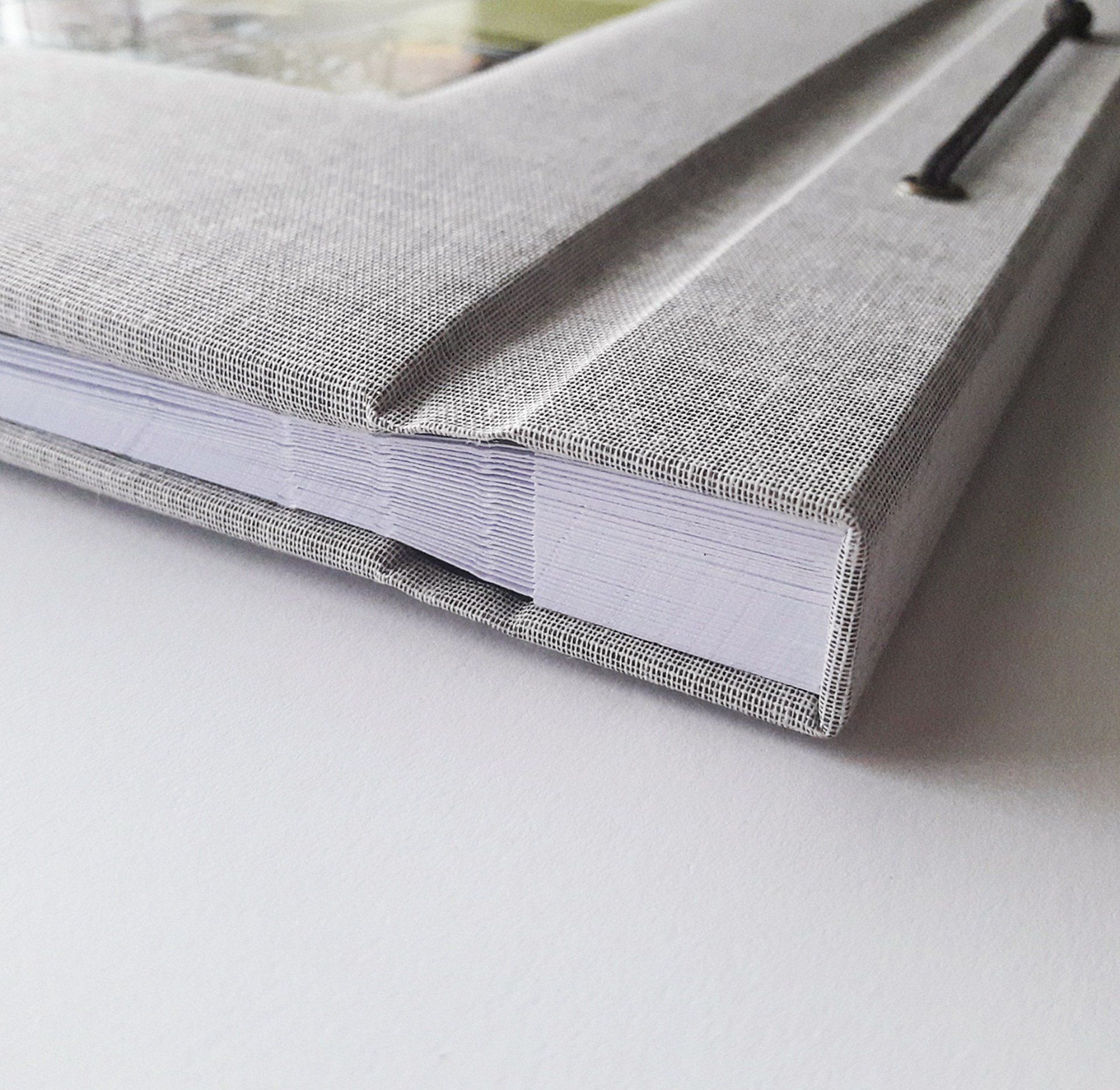 The image shows detail of the Grey linen wedding photo album from the side and white pages can be seen bound together.