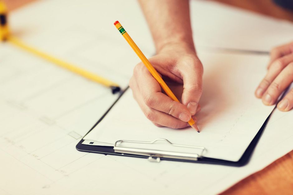 someone writing on the paper using pencil