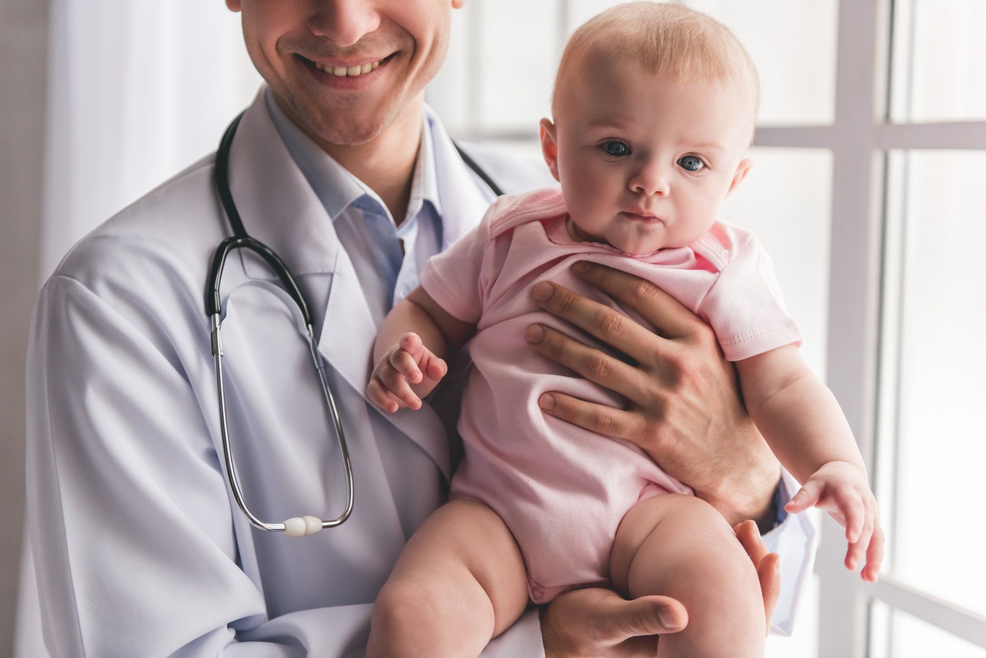 A doctor is holding a baby in his arms.