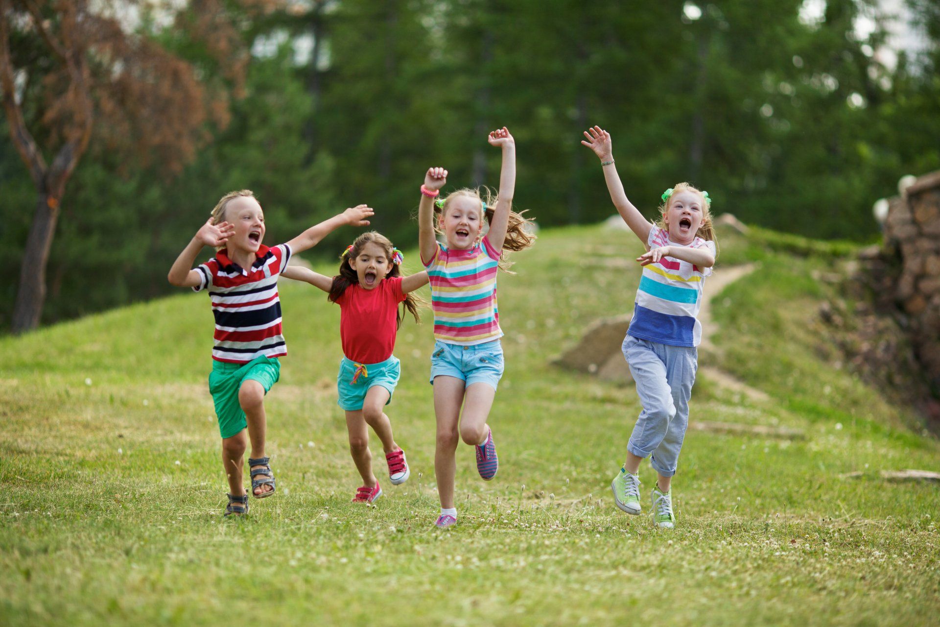A group of children are running through a grassy field.