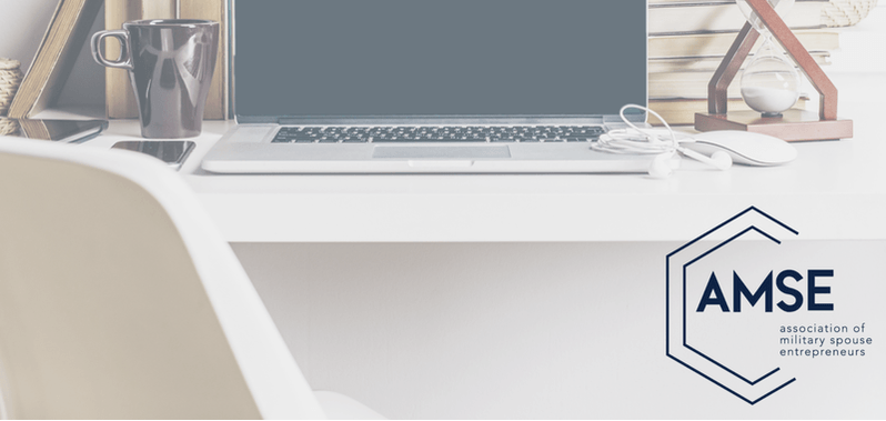 A laptop computer is sitting on a desk next to a chair.