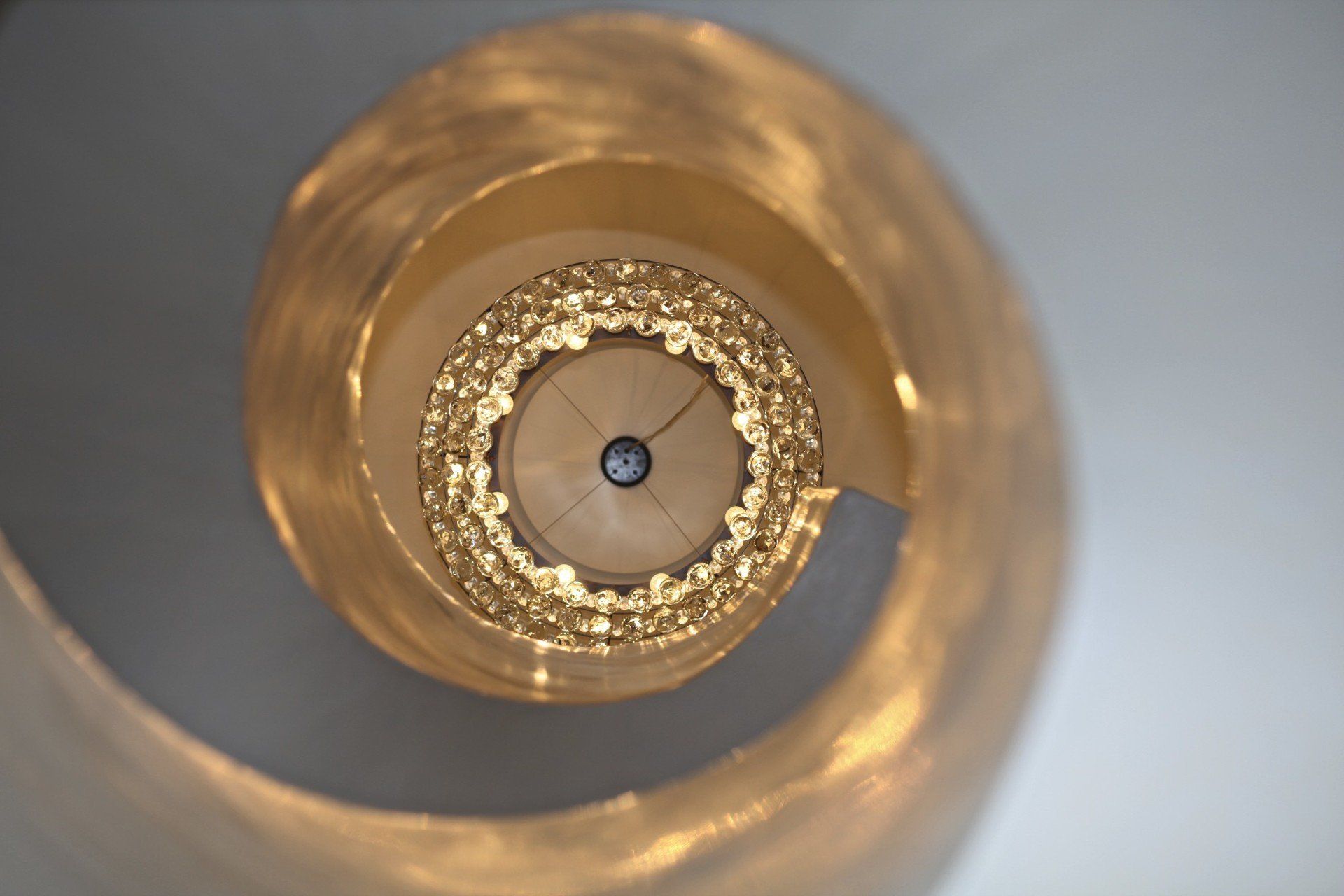 A close up of a spiral staircase with a clock in the middle.