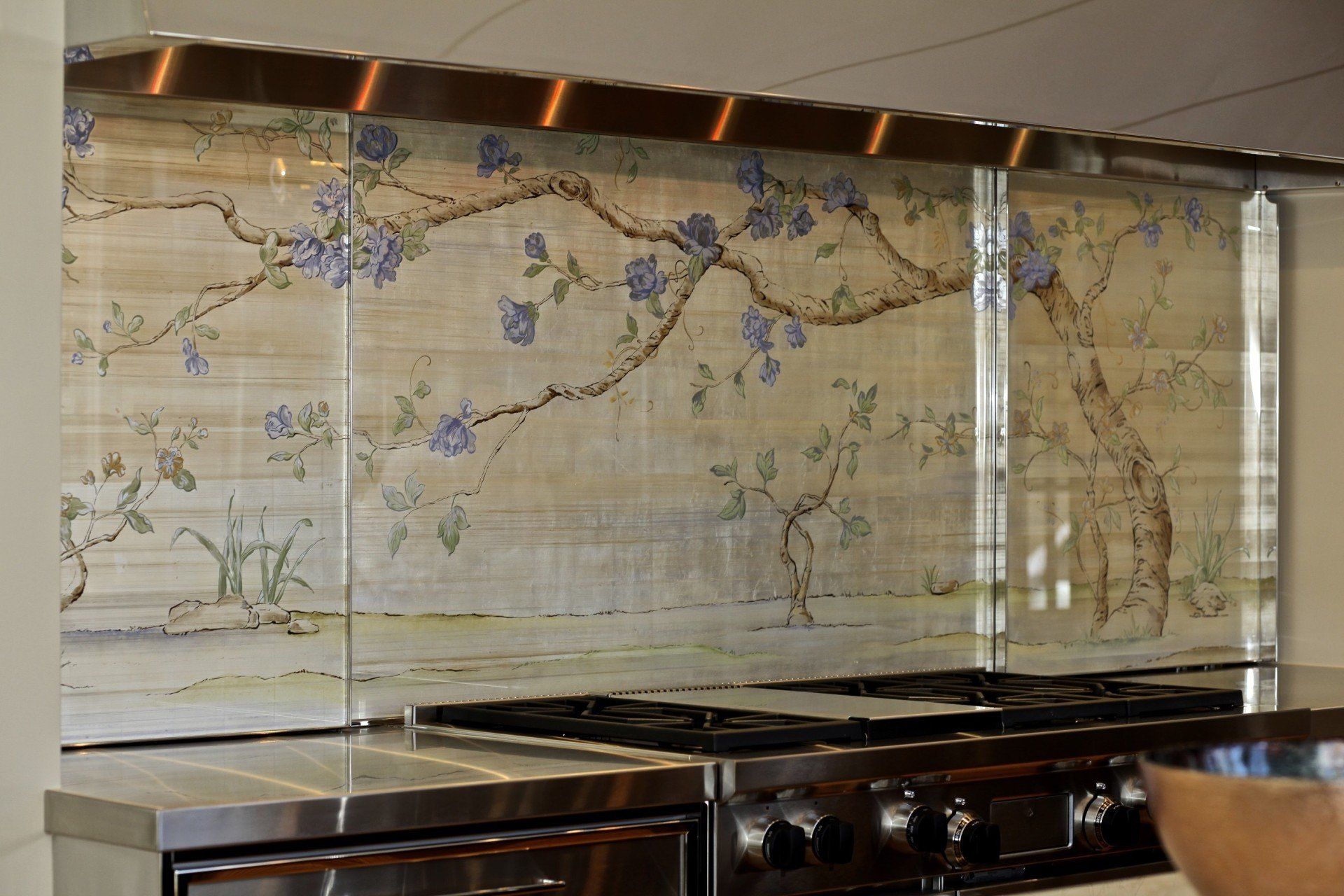 A kitchen with stainless steel appliances and a painting on the wall