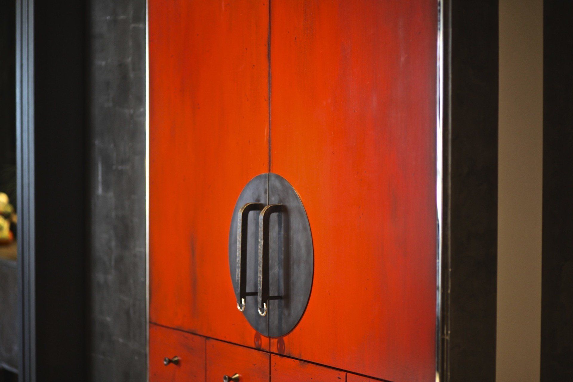 A close up of a red cabinet with black handles in a room.