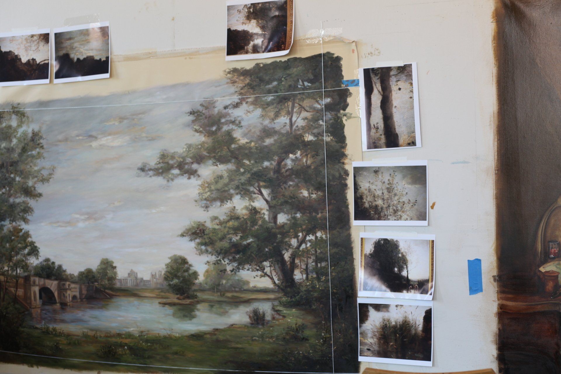A painting of a landscape with trees and a lake is hanging on a wall
