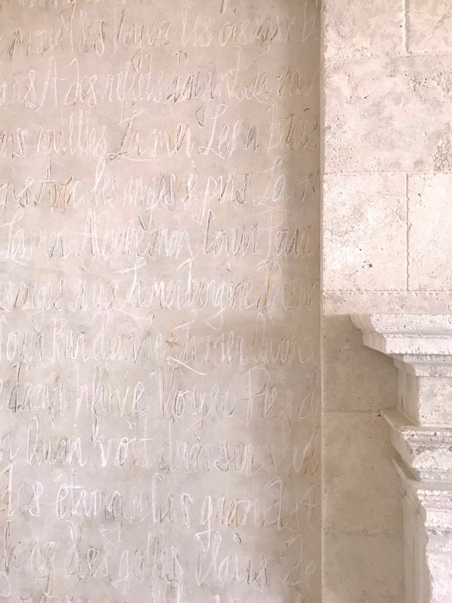 A wall with graffiti on it and a fireplace in the background.