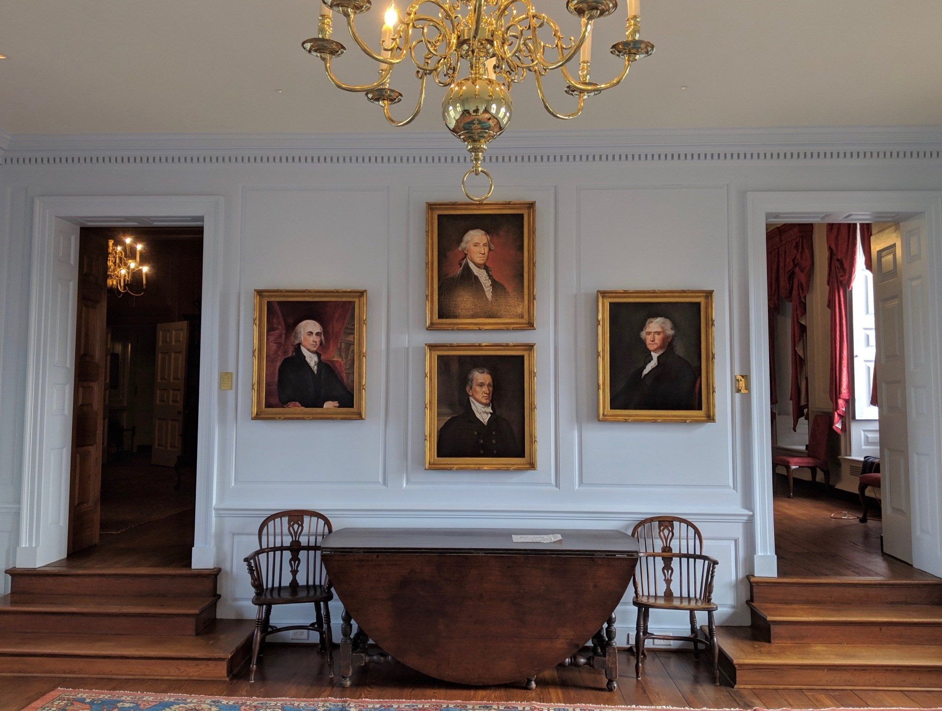 A room with a table and chairs and portraits on the wall