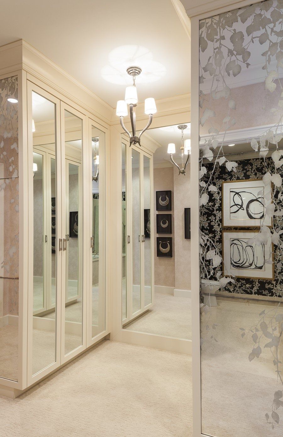 A walk in closet with lots of mirrors and pictures on the wall.