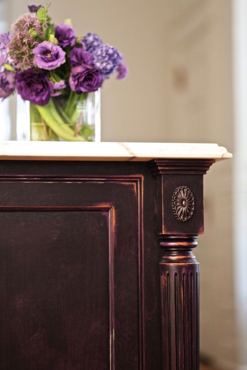 A vase of purple flowers sits on top of a wooden table.