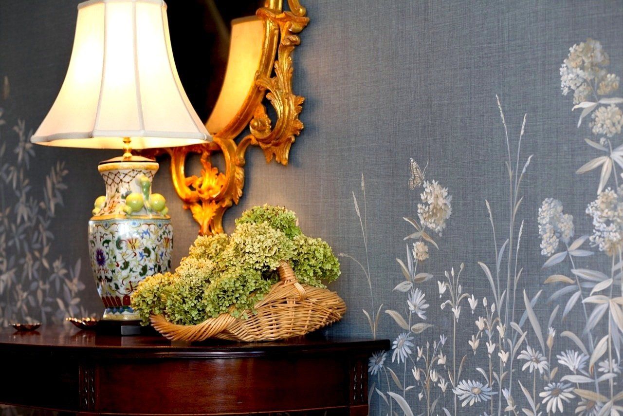 A lamp is sitting on a table next to a basket of flowers.