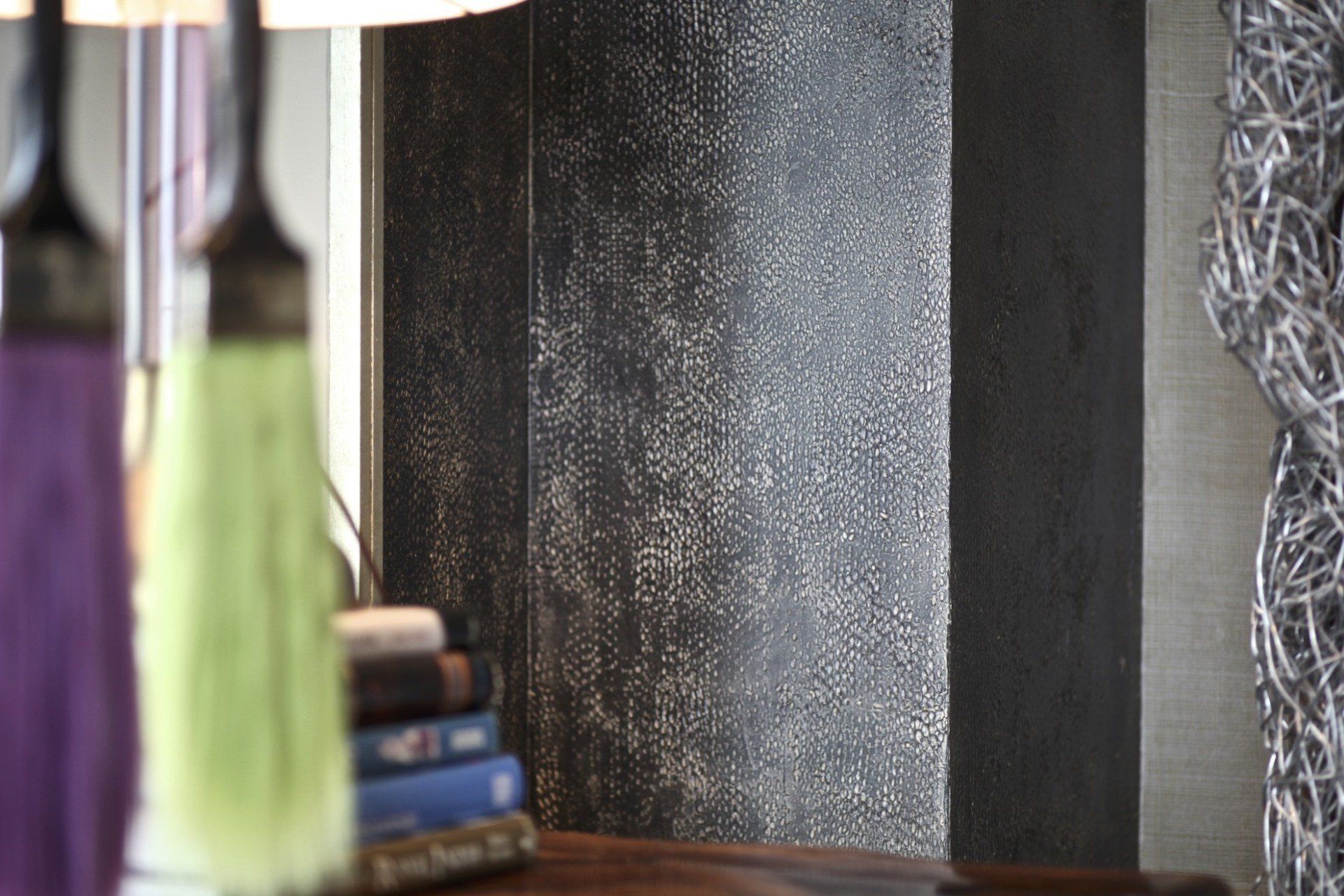 A room with a stack of books and a lamp on a table.